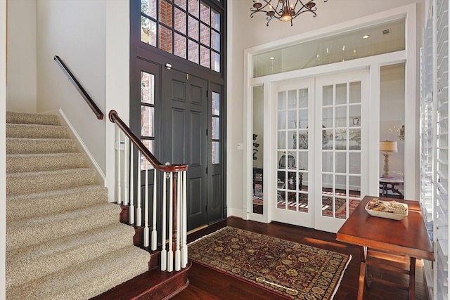 entrance foyer with a notable chandelier, wood-type flooring, and a high ceiling