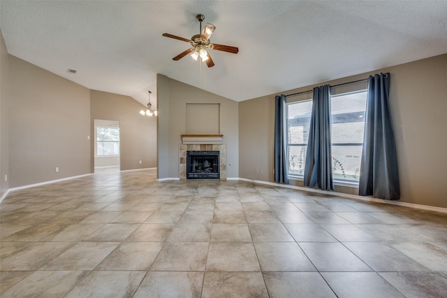 unfurnished living room with ceiling fan with notable chandelier, light tile patterned floors, a fireplace, and vaulted ceiling