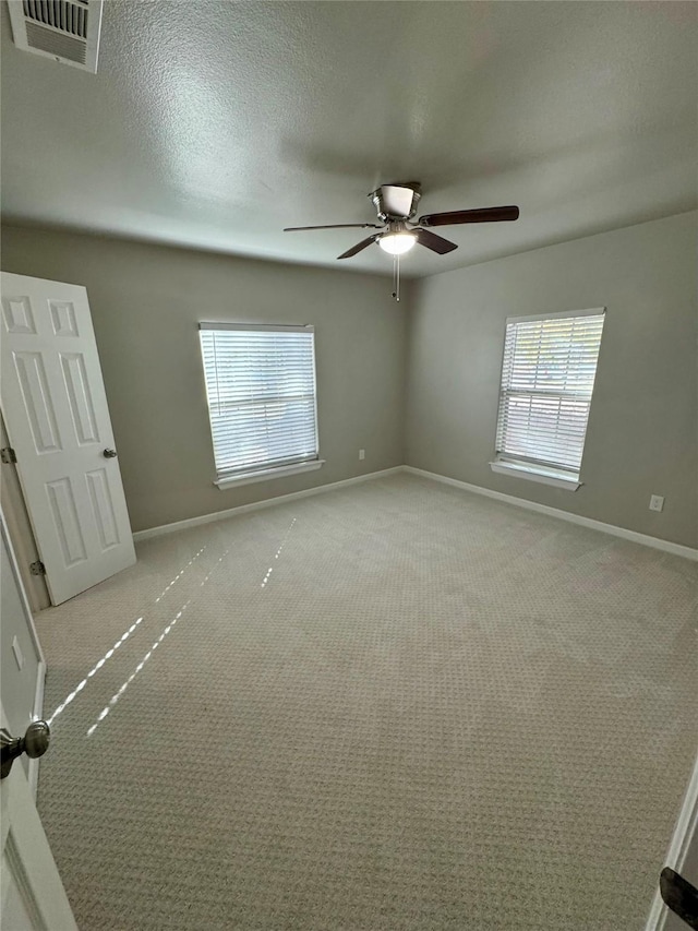 carpeted spare room with ceiling fan and a textured ceiling