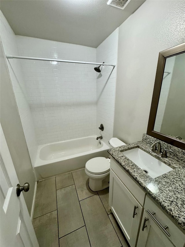 full bathroom with tiled shower / bath, vanity, toilet, and a textured ceiling