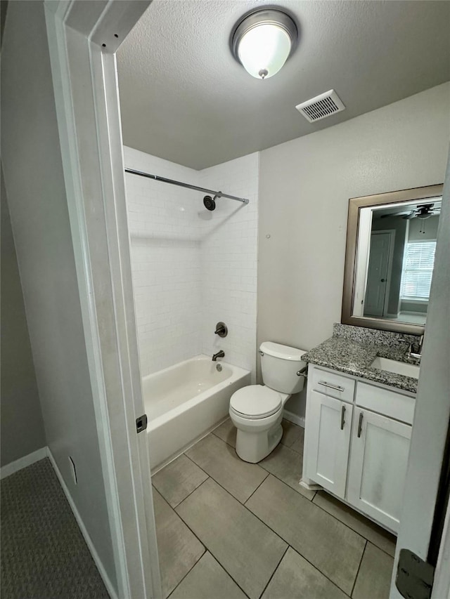 full bathroom with tiled shower / bath, tile patterned flooring, vanity, toilet, and a textured ceiling