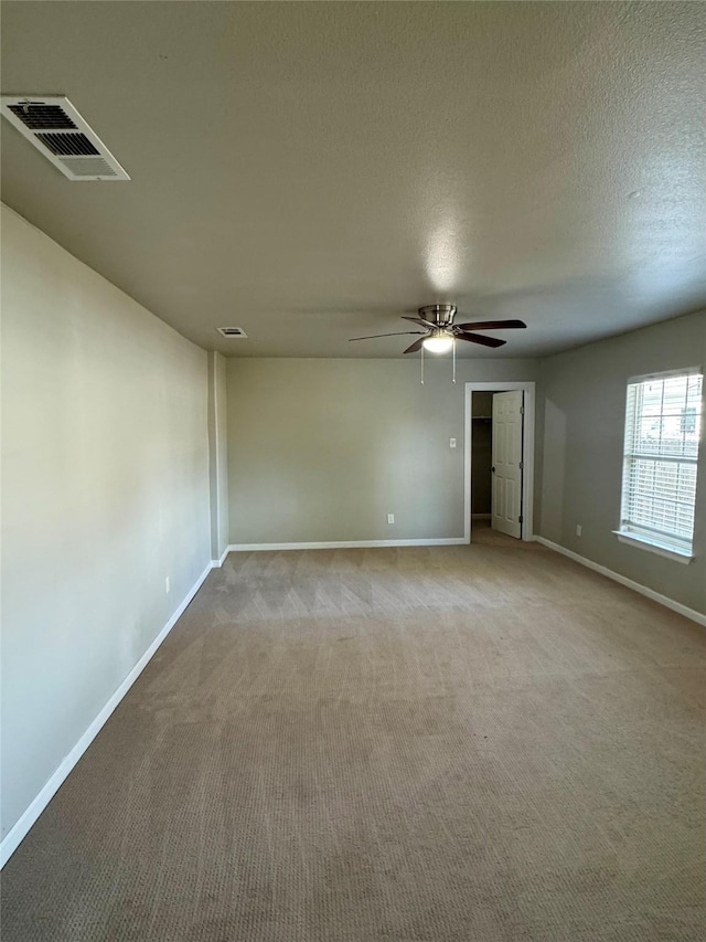 carpeted empty room with ceiling fan and a textured ceiling