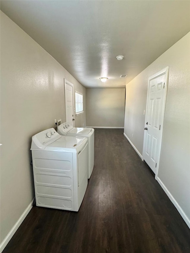 clothes washing area with dark hardwood / wood-style floors and washer and dryer