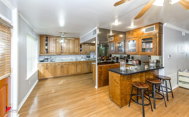 kitchen with a breakfast bar, a center island, ceiling fan, kitchen peninsula, and light wood-type flooring