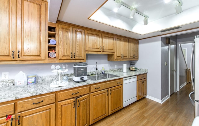 kitchen with sink, light stone counters, hardwood / wood-style floors, white dishwasher, and track lighting