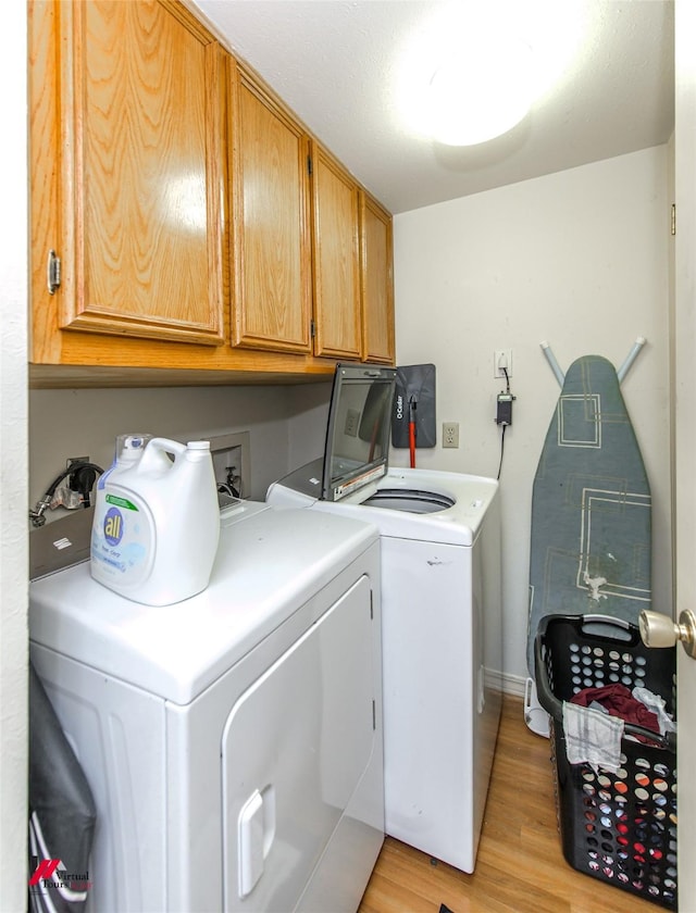 laundry room featuring light hardwood / wood-style flooring, cabinets, and washing machine and clothes dryer