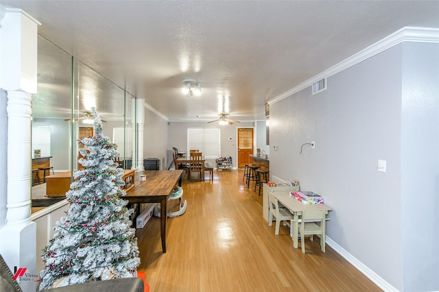 interior space featuring decorative columns, crown molding, and light hardwood / wood-style flooring