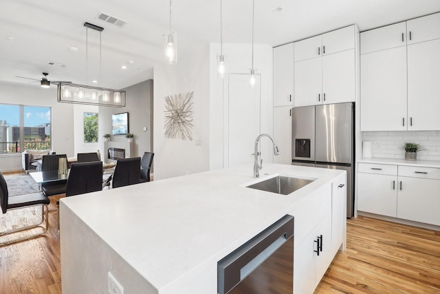 kitchen with white cabinetry, sink, hanging light fixtures, and an island with sink