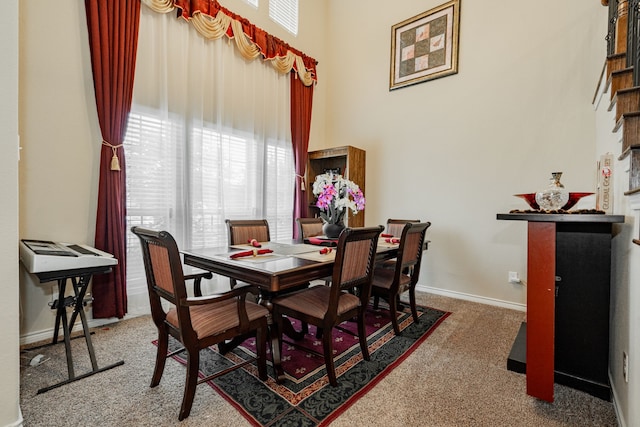 carpeted dining space with a towering ceiling