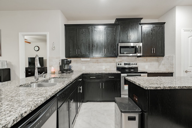 kitchen with decorative backsplash, light stone countertops, stainless steel appliances, ceiling fan, and sink