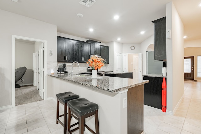 kitchen featuring sink, light tile patterned floors, kitchen peninsula, light stone countertops, and decorative backsplash