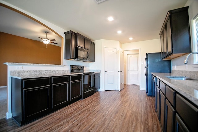 kitchen with black appliances, sink, dark hardwood / wood-style floors, ceiling fan, and light stone countertops