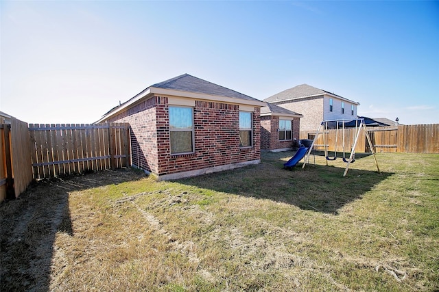 rear view of property with a yard and a playground