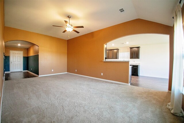 unfurnished living room featuring ceiling fan, dark carpet, and vaulted ceiling