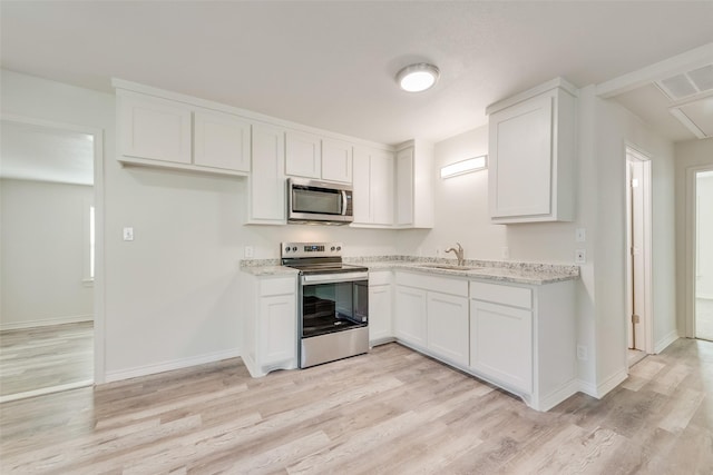 kitchen featuring light stone countertops, appliances with stainless steel finishes, sink, white cabinets, and light hardwood / wood-style floors