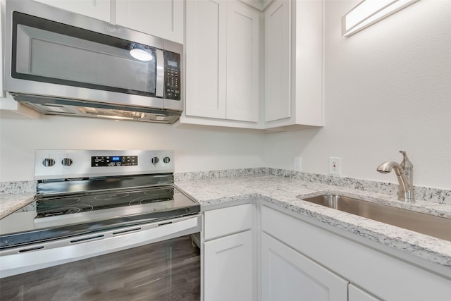 kitchen with light stone countertops, sink, white cabinets, and stainless steel appliances