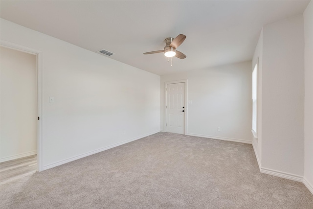 empty room with a healthy amount of sunlight, ceiling fan, and light colored carpet