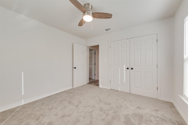 unfurnished bedroom with ceiling fan, light carpet, and a closet