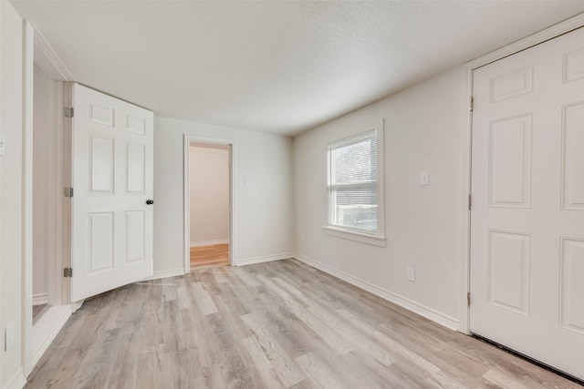 unfurnished bedroom with light wood-type flooring, a textured ceiling, and a closet