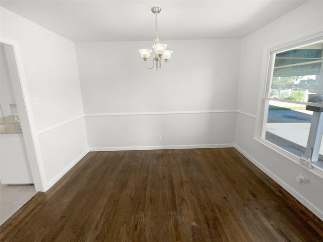 spare room featuring dark hardwood / wood-style floors and a chandelier