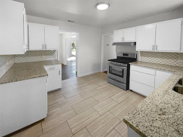 kitchen featuring white cabinetry, gas stove, backsplash, and light stone counters