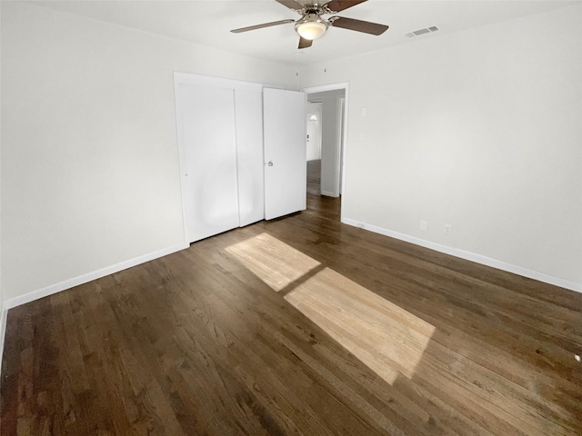 unfurnished bedroom featuring a closet, dark hardwood / wood-style floors, and ceiling fan