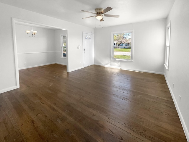 empty room with ceiling fan with notable chandelier and dark hardwood / wood-style flooring