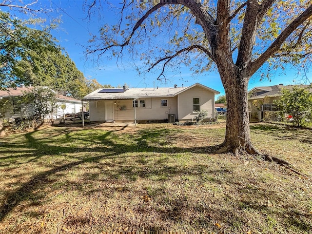 rear view of property with a lawn and solar panels