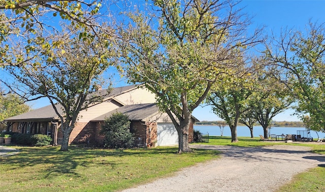 view of front facade featuring a garage, a water view, and a front lawn