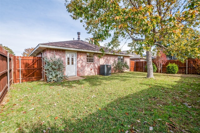 rear view of house featuring a lawn and central AC unit