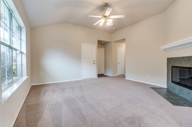 unfurnished living room with dark colored carpet, lofted ceiling, a fireplace, and a wealth of natural light