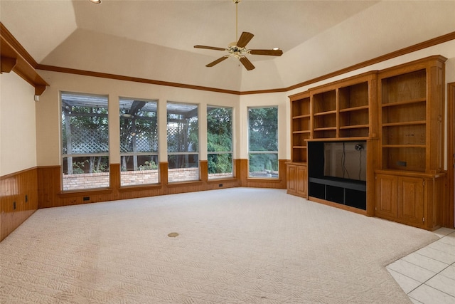 unfurnished living room featuring lofted ceiling, wooden walls, light carpet, and ceiling fan