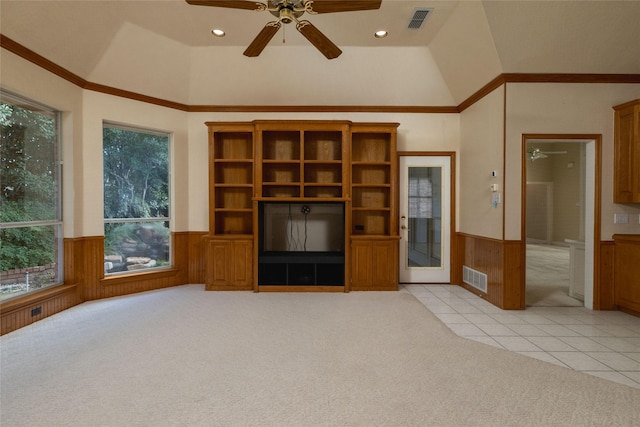 unfurnished living room with light carpet, vaulted ceiling, ceiling fan, crown molding, and wood walls