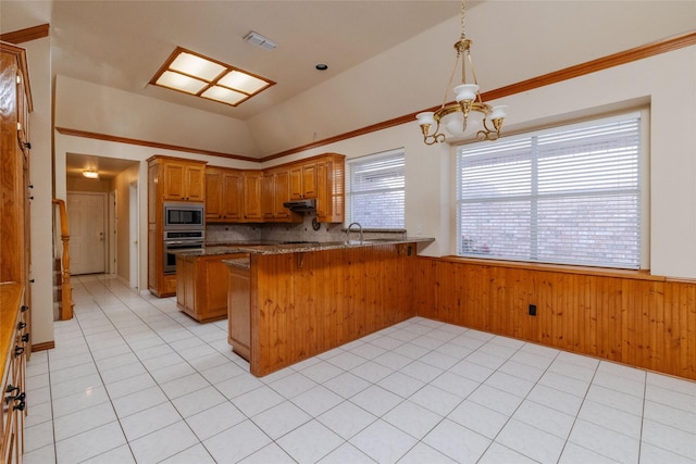 kitchen with lofted ceiling, wooden walls, tasteful backsplash, kitchen peninsula, and stainless steel appliances