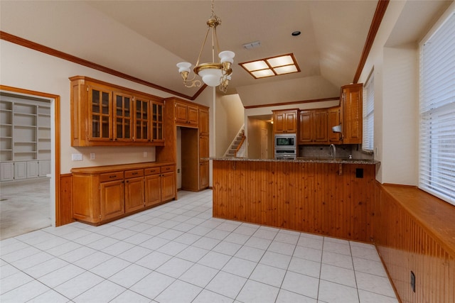 kitchen with vaulted ceiling, a notable chandelier, kitchen peninsula, stainless steel appliances, and crown molding