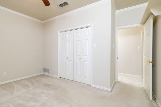 unfurnished bedroom featuring light colored carpet, a closet, crown molding, and ceiling fan