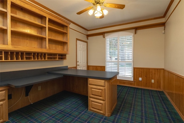 unfurnished office with built in desk, ornamental molding, wooden walls, and ceiling fan