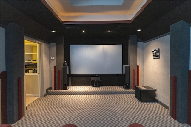 carpeted home theater room with a tray ceiling