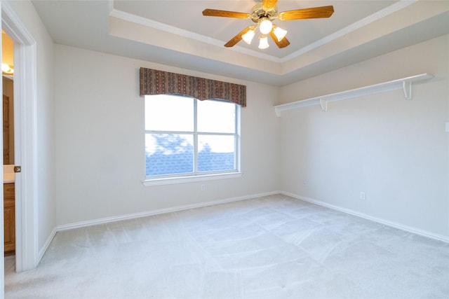 carpeted empty room with a tray ceiling, ceiling fan, and ornamental molding