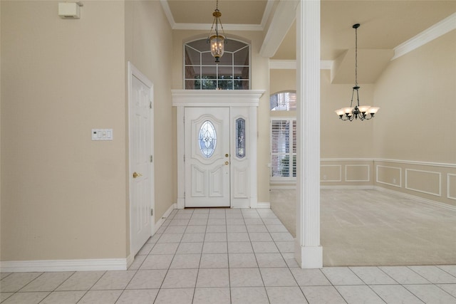 tiled foyer with a high ceiling, ornamental molding, and a chandelier