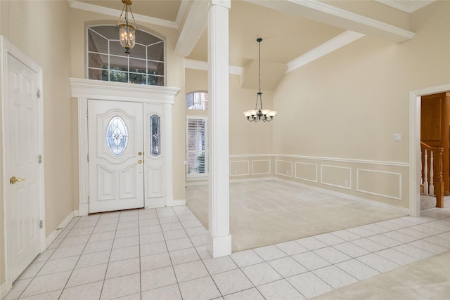 carpeted entryway featuring crown molding, a towering ceiling, and an inviting chandelier