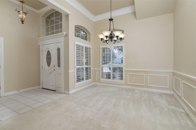 carpeted foyer featuring a towering ceiling, ornamental molding, and a chandelier