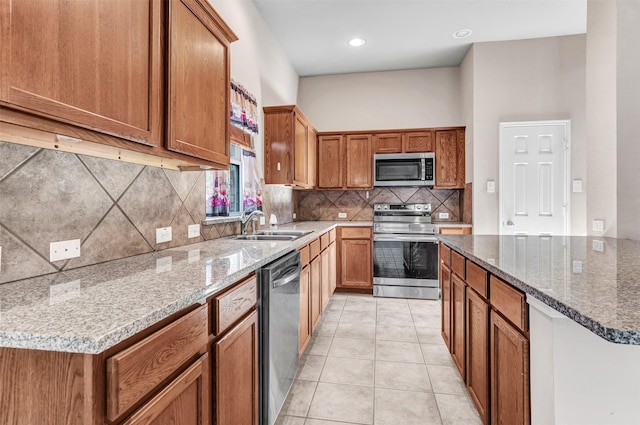 kitchen featuring light tile patterned floors, stainless steel appliances, light stone counters, and sink