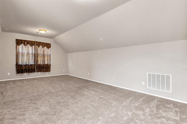 carpeted empty room with lofted ceiling