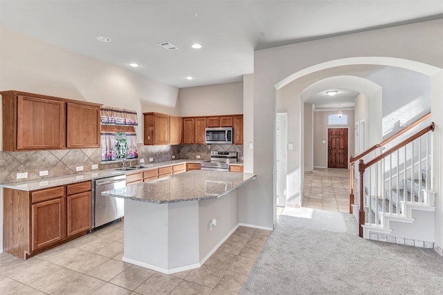 kitchen with sink, stainless steel appliances, light stone counters, decorative backsplash, and light tile patterned floors