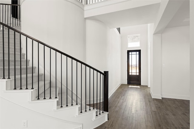 foyer featuring stairs, a high ceiling, baseboards, and wood finished floors