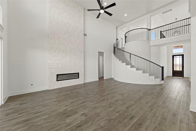 unfurnished living room with visible vents, baseboards, stairs, a fireplace, and wood finished floors