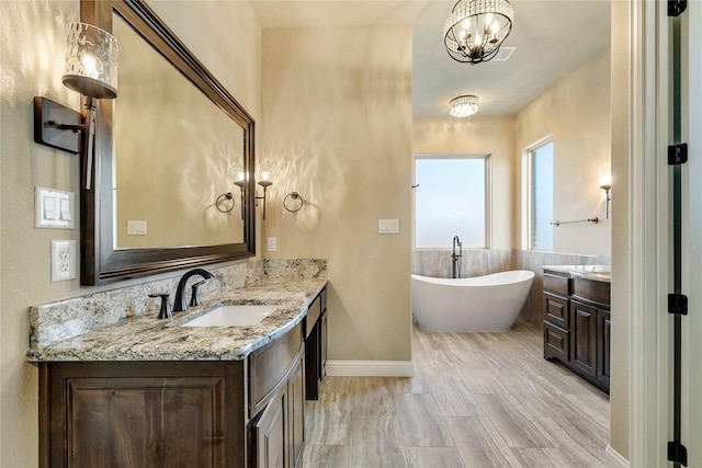 bathroom featuring a bathing tub, vanity, wood-type flooring, and an inviting chandelier