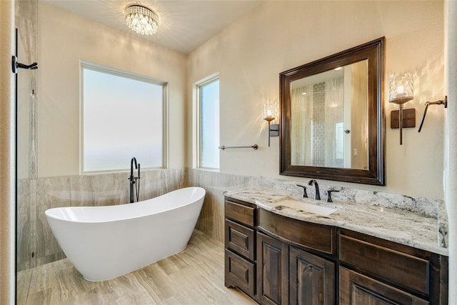 bathroom featuring vanity, an inviting chandelier, tile walls, and a bathing tub