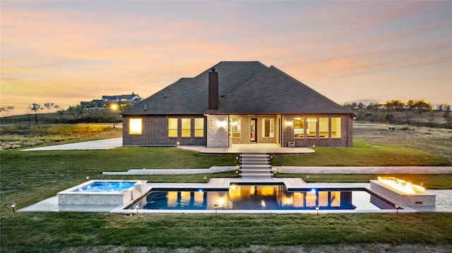 back house at dusk with a lawn, an in ground hot tub, and an outdoor fire pit